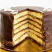 Gambino's Chocolate Doberge Cake, sliced showing multiple layers of yellow sponge cake with chocolate frosting and a glossy chocolate glaze on top.