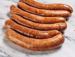 Comeaux's Pork Boudin 1lb, image of cooked, freshly made pork boudin sausages with a golden-brown exterior arranged in a row on a surface.