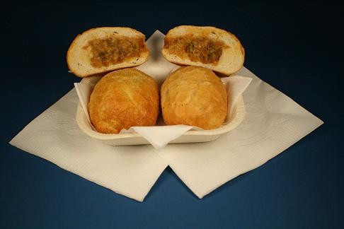 Cajun Original Crawfish Pistolettes 24pk, fried breaded crawfish-filled pastries on a white napkin with some cut open showing crawfish filling inside.