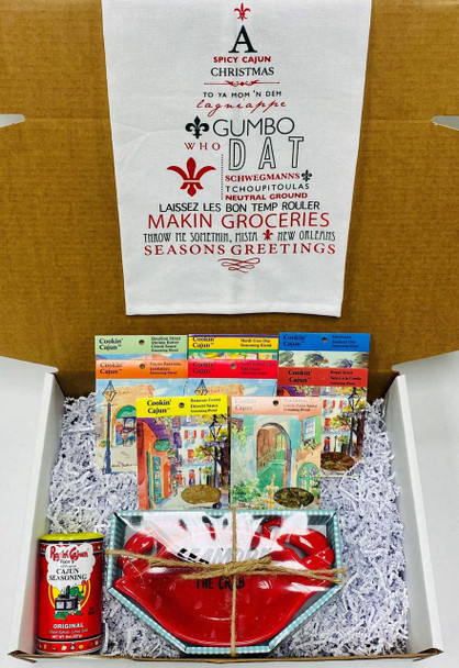 Creole Foods of Louisiana Dat Dip Gift Box, a festive gift box with various seasonings, a red ceramic dish, and a can of Cajun seasoning, arranged on shredded paper inside a white box, ideal for holiday or special occasion gifting.