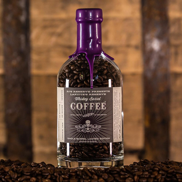PJ's Whiskey Barrel Aged Coffee - Limited Edition, bottle filled with roasted coffee beans and purple wax seal, surrounded by scattered coffee beans.