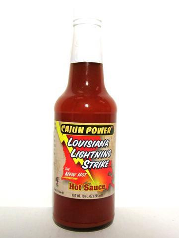 Cajun Power Lightning Hot Sauce 10oz, a bottle of hot sauce with a red liquid and a yellow, black, and red label featuring the product name and description.