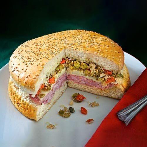 Carnival 8" Whole Muffuletta, sliced open to reveal layers of cured meats, cheese, and chopped vegetables in a sesame seed bun.