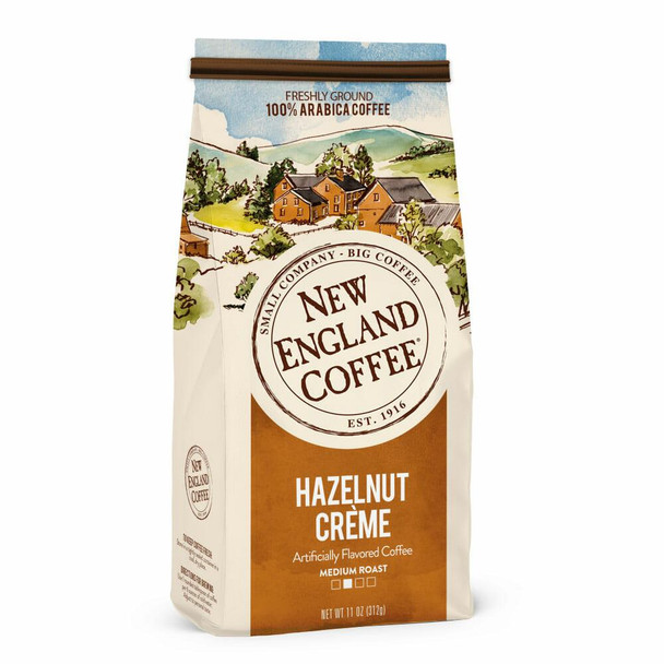 New England Coffee Hazelnut Creme Ground 11 oz, illustrated packaging of coffee with a scenic countryside drawing and label highlighting the flavor and roast level.