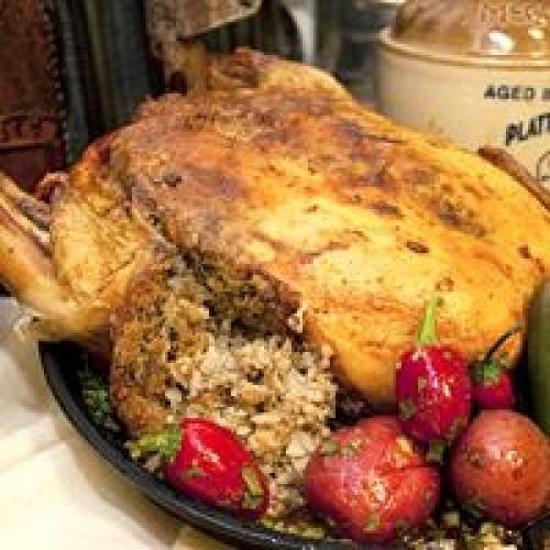 Comeaux's Stuffed Chicken with Crawfish, a large roasted chicken stuffed with crawfish and served with fresh red radishes and green vegetables.