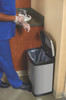 1901992 - A stainless steel Rubbermaid Slim Jim Front Step Pedal Bin with lid open being used by a worker in blue scrubs