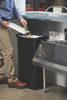 1883613 - A worker scrapes food scraps into a black Rubbermaid Slim Jim Front Step Pedal Bin that is situated in a kitchen