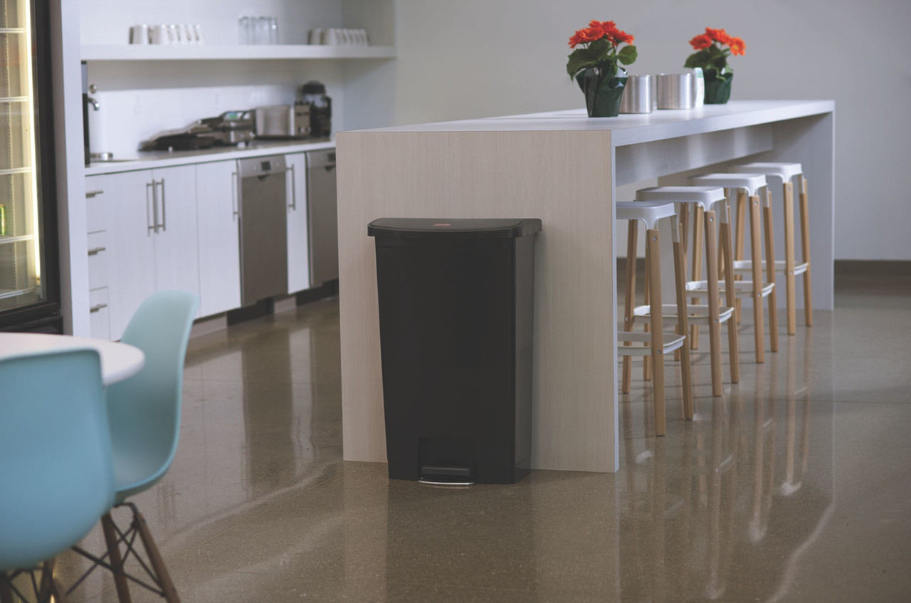 1883613 - A black Rubbermaid Slim Jim Front Step Pedal Bin placed against a central counter in a domestic kitchen