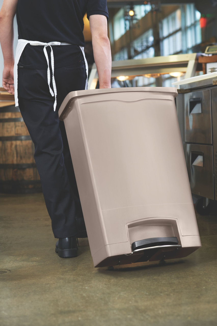 1883552 - A kitchen worker with bin tilted back onto its rear wheels pulls the bin through a kitchen