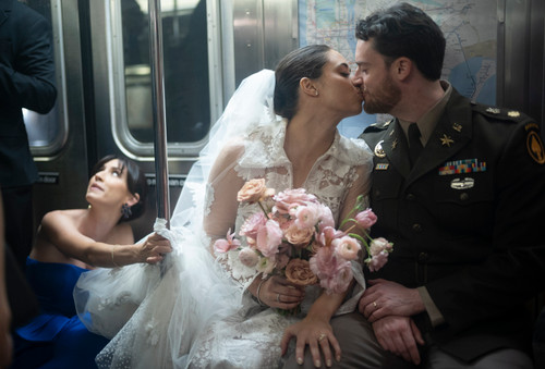Bride and groom sharing a kiss on a subway train during their wedding day