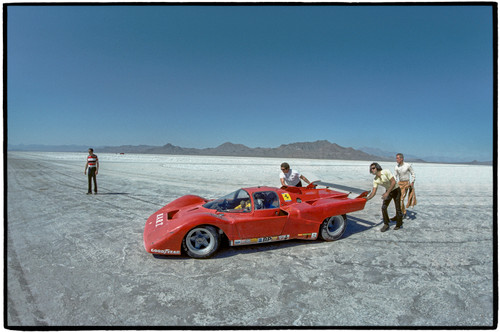 Red race car on salt flats being pushed by the crew