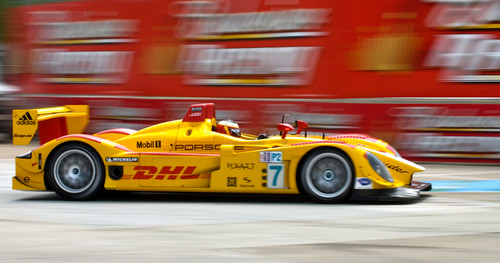 Yellow F1 car driving past red blurred background