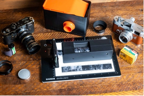 Film cameras, light meter, film rolls, and developing tools arranged on wooden table