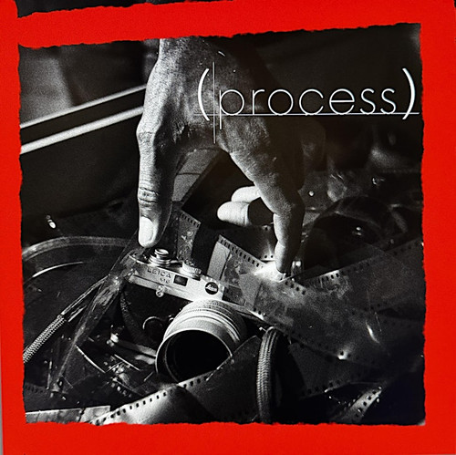 Hand selecting a Leica film camera from strips of developed negatives emphasizing tactile editing and photographic process