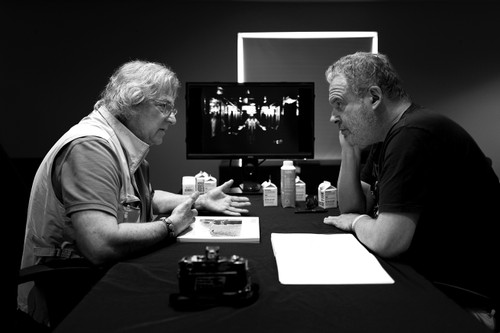 Two people seated at a table reviewing photographs during a focused critique session