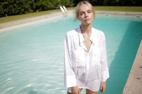 Portrait subject standing by outdoor pool in natural light