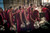 Monks in red robes moving through a communal space conveying ritual, movement, and daily life