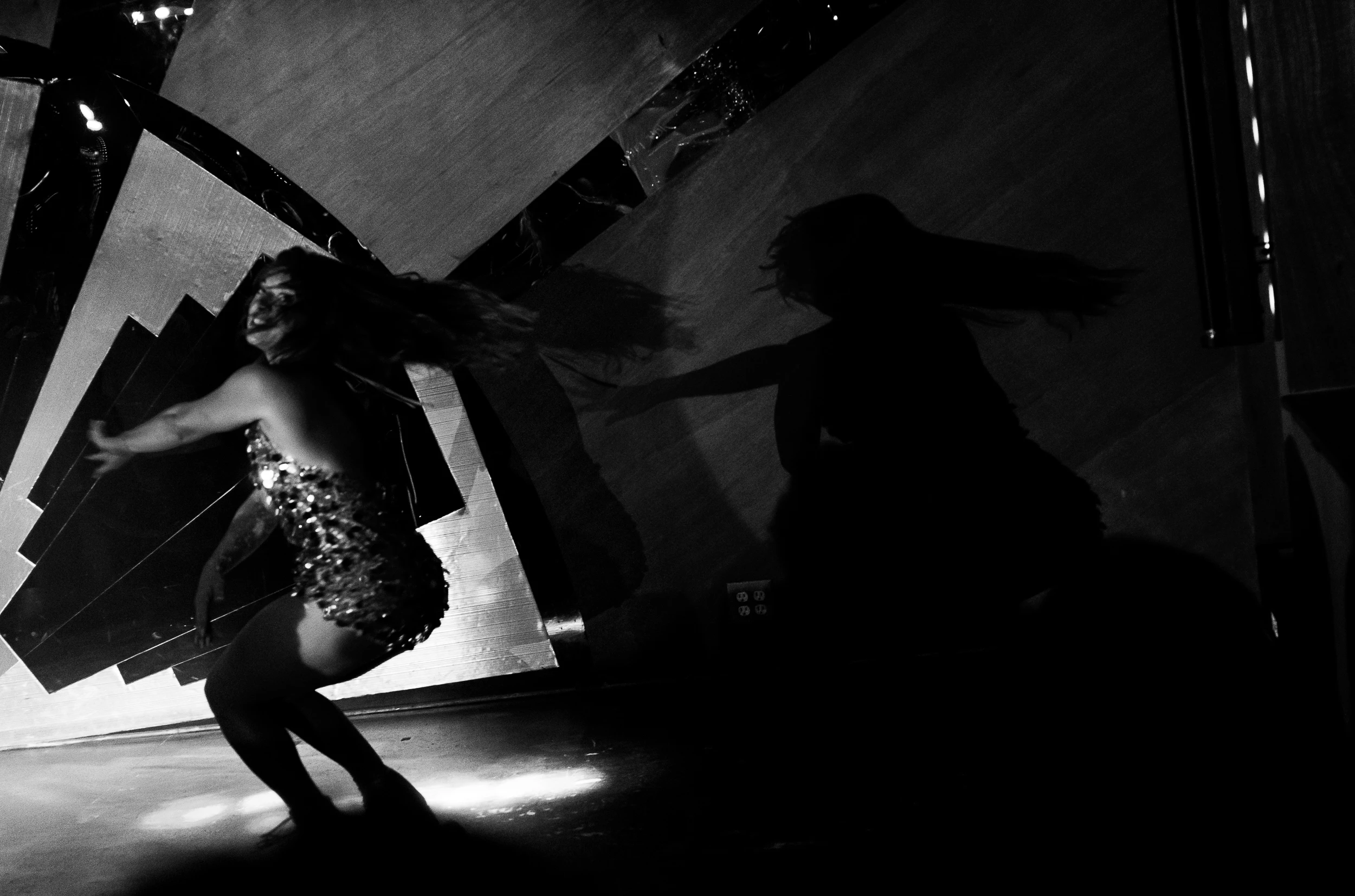 Black-and-white photograph of a performer moving through dramatic light and shadow