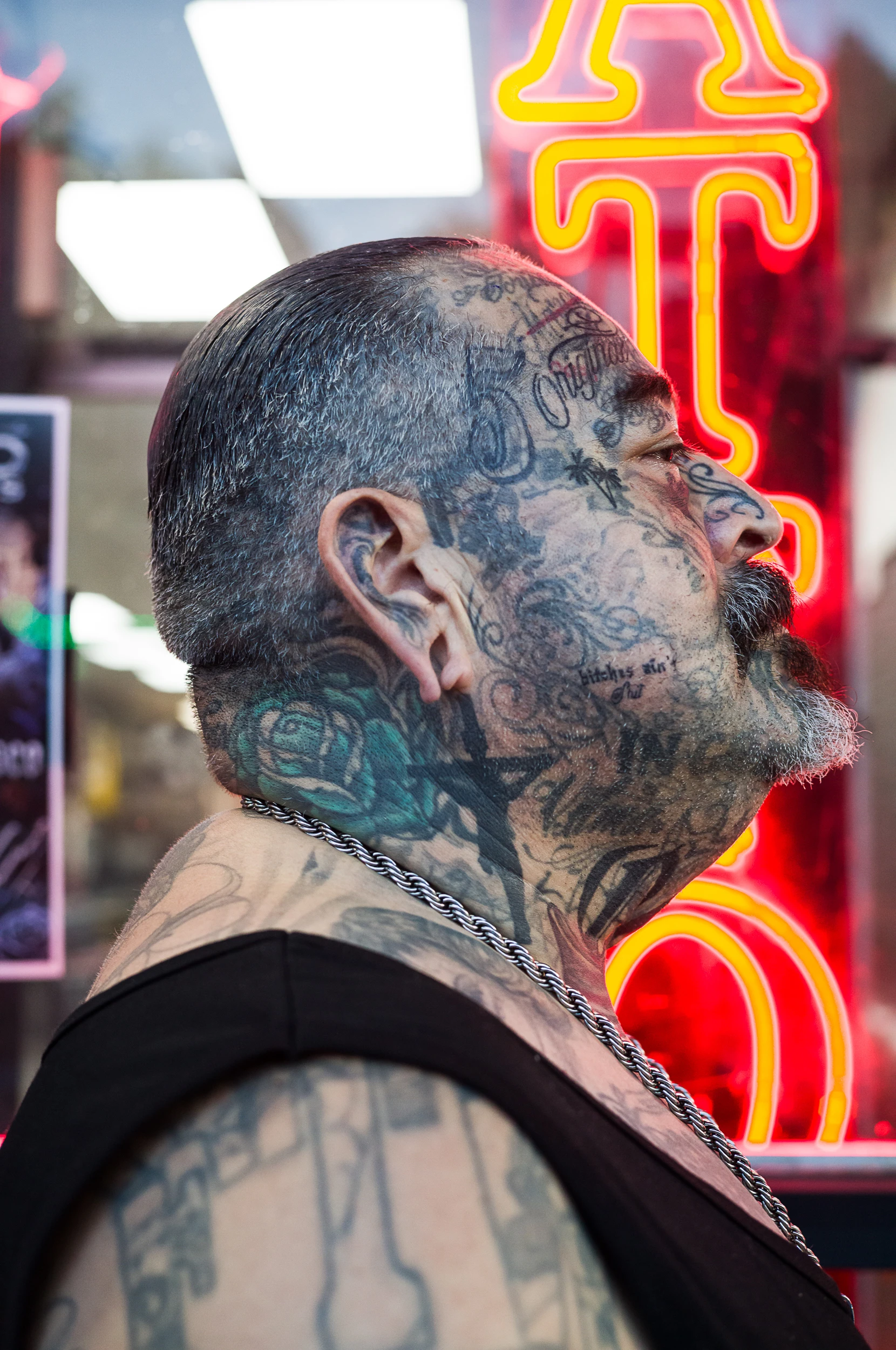 Profile portrait of a tattooed man against illuminated signage