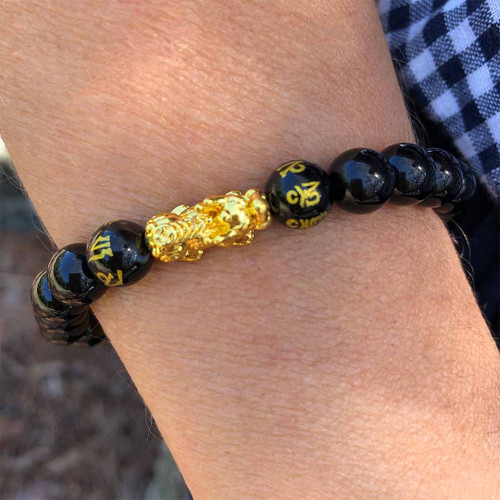 Pixiu Om Black Obsidian 8mm Bead Bracelet on wrist and checkered shirt behind