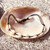 Cowrie Shell Black Braided Adjustable Bracelet resting on shell with stone behind