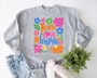“Teach. Love. Inspire.” in multicolored script with floral accents