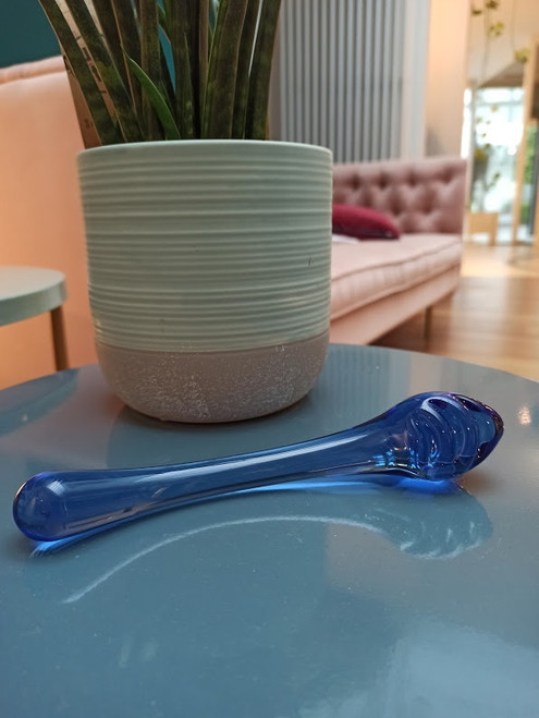 Bibi glazen dildo naast een plant op een salonstafel