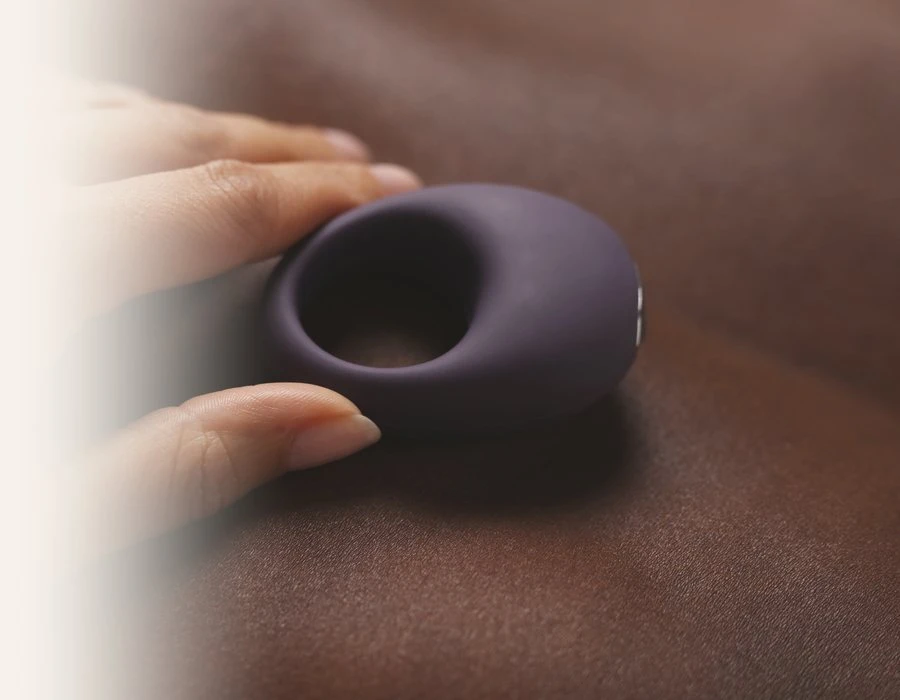 Paarse Je Joue Mio vibrerende penisring van silicone op een bruin satijnen laken