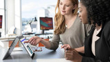 Refurbished Two women in a professional setting working on a Lenovo ThinkPad X1 Yoga laptop that is opened to show its display and
