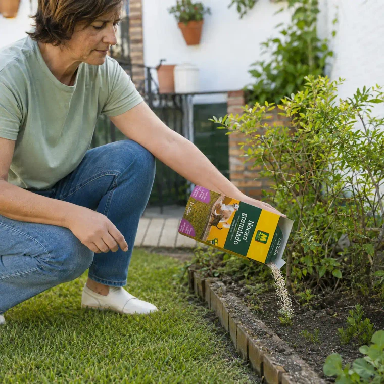 Mujer aplicando repelente granulado Nocan para perros y gatos en el jardín