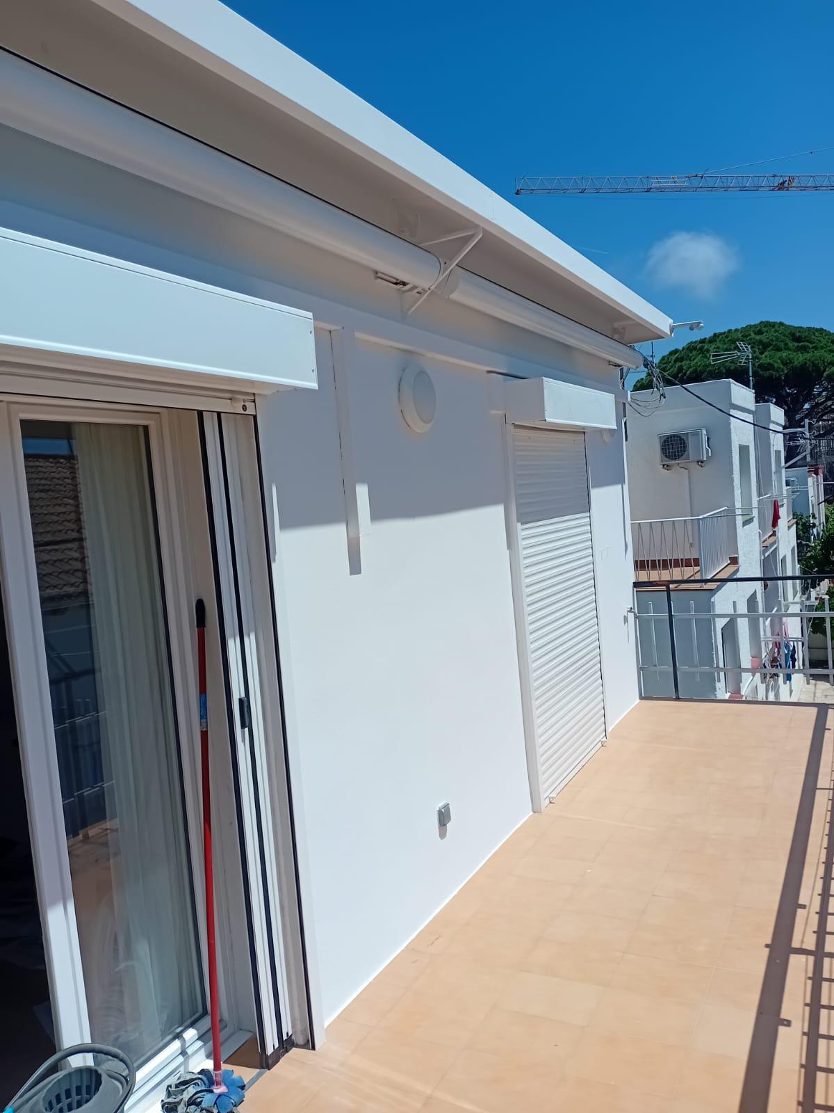 Fachada blanca terminada junto a una terraza exterior