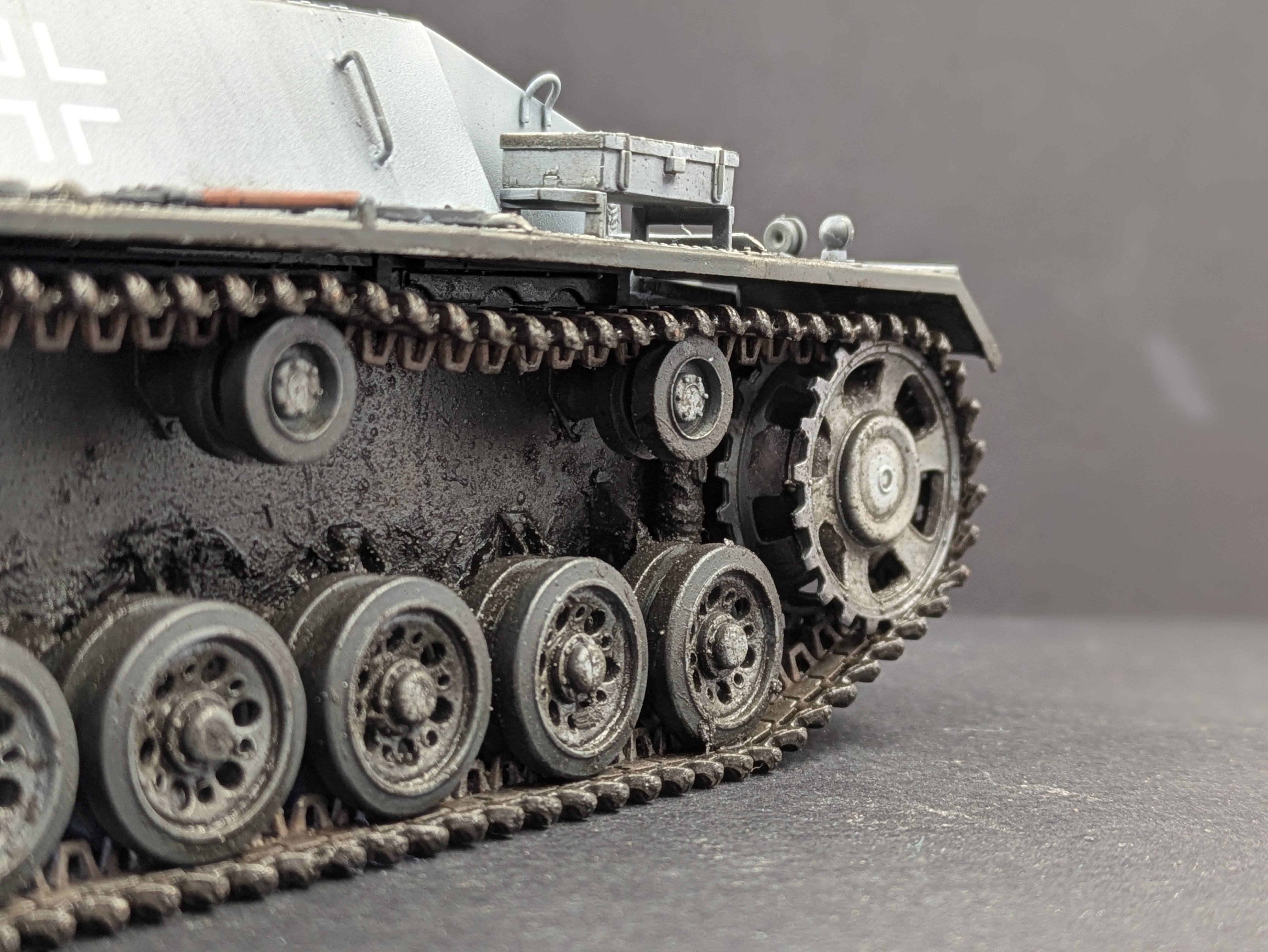 Side close-up of tracks and wheels showing mud accumulation and wet shine