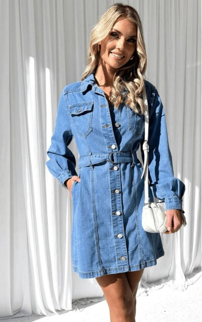 Model wearing the Georgia denim dress in mid blue, a long sleeve button-down belted denim mini dress styled with heels