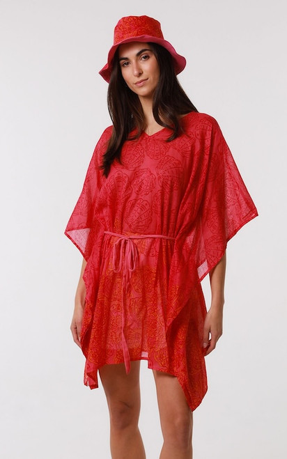 Model wearing the Solstice Shell resort wear co-ord set. The set features a hot pink and orange seashell-print V-neck kaftan cover-up with ribbon wrapped around waist, paired with a matching unstructured hot pink patterned beach bucket hat.