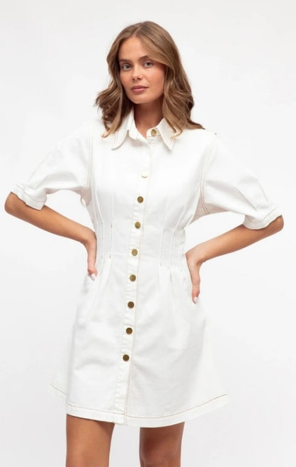 Model wearing the Louisa denim shirt dress in white with a collared neckline, gold buttons, short sleeves and a flattering fitted waist.