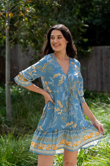With its sweet boho inspired pattern and border print, our floaty Erica Boho Dress is perfect for weekends away or brunches with friends. Pair with sandals on warm summer days or boots on cooler autumn days.

This dress features:

V-neckline 
Button up bust and mid section
Wooden buttons
Long sleeves with elasticised cuffs and frill detail
Functional drawstring tie
Frilled hem with border print
Colour: Denim Blue with Yellow Floral Detail

Fabric: 100% Viscose

Size Guide: True to size.