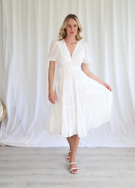 You will feel like a Bohemian Goddess in our beautiful Kimberly Midi Dress! This dress features a stunning sheer shell with stripe detail, puff sleeves and a tiered skirt which make it perfect to wear anywhere from a fancy day event to a garden picnic! Pair with our Ibiza Strappy Slides in Camel or tan heels to complete the look.

This dress features:

V-neckline
Button up front
Sheer shell with stripe detail
Shirred waist at back
Short sleeves with elasticised cuffs
Tiered skirt with ruffle hemline
Midi length
Lined skirt
Colour: White

Fabric: 100% Polyester

Size Guide: True to size. Stick with your usual size.