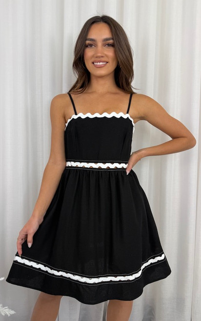 Make a statement in our Elle Linen Blend Ric Rac Dress – a bold and playful addition to your spring/summer wardrobe. Featuring crisp white ric rac trim against a black linen blend, this dress brings retro charm with a modern twist. The square neckline with adjustable straps and the flared skirt create a flattering, feminine silhouette that’s as comfortable as it is eye-catching. Perfect for picnics, parties, or festive days out, this dress is made to stand out and turn heads.

This dress features:

Square neckline
Adjustable straps
A-line skirt
Invisible zip on the side
Ric rac trim
Knee length
Unlined
Colour: Black with White Ric Rac Trim

Fabric: 70% Linen, 30% Viscose

Size Guide: True to size. Model is wearing a size 8.