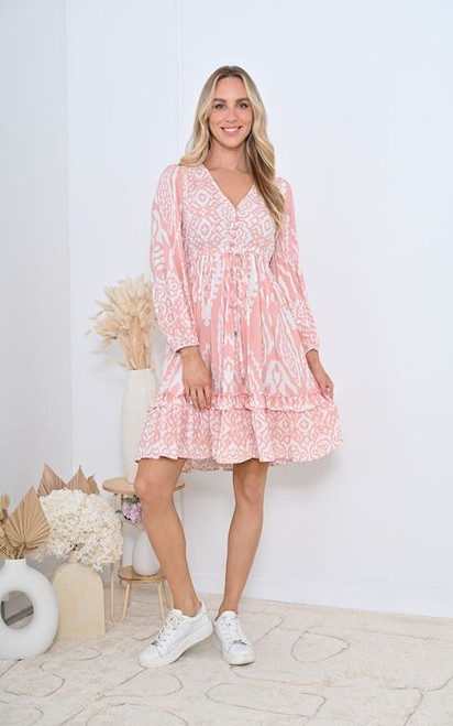 Turn heads in our Valerie Boho Dress, a playful yet elegant piece designed for everyday wear. Featuring a soft pink base with a chic white ikat-inspired print, this mini dress is perfect for brunch dates, weekends away, or casual catch-ups with friends. The relaxed silhouette, V-neckline, and floaty long sleeves make it both comfortable and flattering, while the tiered hem adds a feminine touch. Pair with sneakers for a laid-back daytime look, or style with wedged heels and silver accessories for an effortless day-to-night outfit.

This dress features:

V-neckline
Functional drawstring waist with silver caps
Long, balloon sleeves
Button up bust
Tiered skirt
Ruffled hemline
Unlined
Colour: Pink with White Print

Fabric: 100% Rayon

Size Guide: True to size. Model wears a Size 8.