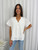 Experience the perfect blend of comfort and charm with our stunning Marina Broderie Anglaise Blouse. This exquisite top features intricate, cotton broderie anglaise detailing, creating a delicate and eye-catching texture. The flattering V-neckline and relaxed short sleeves offer a comfortable yet stylish look, perfect for warm weather days. Whether you're strolling through a sun-drenched market or enjoying a casual brunch with friends, this versatile top adds a touch of timeless elegance to any outfit, making it a must-have staple for your spring/summer wardrobe. Pair with your favourite denim, skirt or pants and statement earrings.

This blouse features:

V-neckline
Mandarin collar
Short sleeves
Button through front
Hi-Low design
Relaxed fit
Lined body
Colour: White

Fabric: 100% Cotton; Lining: 100% Rayon.

Size Guide: True to size - relaxed fit.