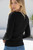 Black Maxine Ribbed Knit Top with gold button henley neckline and fitted ribbed fabric styled with high-rise blue jeans.