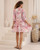 Model wearing pink floral Annabelle babydoll mini dress with button front, pockets and flowy sleeves