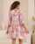 Model wearing pink floral Annabelle babydoll mini dress with button front, pockets and flowy sleeves