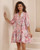 Model wearing pink floral Annabelle babydoll mini dress with button front, pockets and flowy sleeves