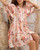 Model wearing orange and pink floral Annabelle babydoll mini dress with button front, pockets and flowy sleeves