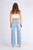 Model wearing the Cassandra high-waisted wide leg jeans in light blue denim, paired with a white sleeveless crop top and white square-toe mules