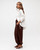Woman wearing chocolate-brown Janet balloon pants with an elasticated waist and gathered ankle cuffs, styled with a white button-up shirt and sandals.