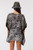 Model wearing the semi-sheer Midnight Palm monochrome tropical print chiffon kaftan with a cinched drawstring tassel waist, featuring a striking saffron yellow and white geometric border on the sleeves and asymmetrical hem.