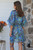 Model wearing the Electric Safari Kaftan cover-up featuring a vibrant zebra print pattern with a gathered elastic waist and blue tassel details.