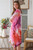 Model wearing the semi-sheer Sunset Blossom kimono. The open-front chiffon kimono features a vibrant mix of coral red, hot pink, magenta, and lavender abstract watercolour shapes layered over a solid white top.